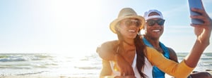 woman and man taking a selfie during sunset on the beach