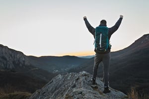 hiker standing on top of a mountain