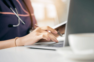 nurse typing at a laptop