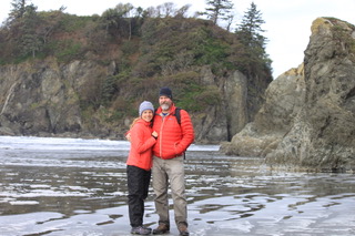 Allied traveler and her husband standing together in the Olympic National Forest on a sunny winter day