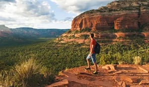 male hiker on the edge of a mountain looking out into a valley
