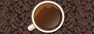 coffee cup filled with coffee sitting on coffee beans